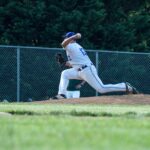 A baseball pitcher is captured in mid-throw on a sunny outdoor field.