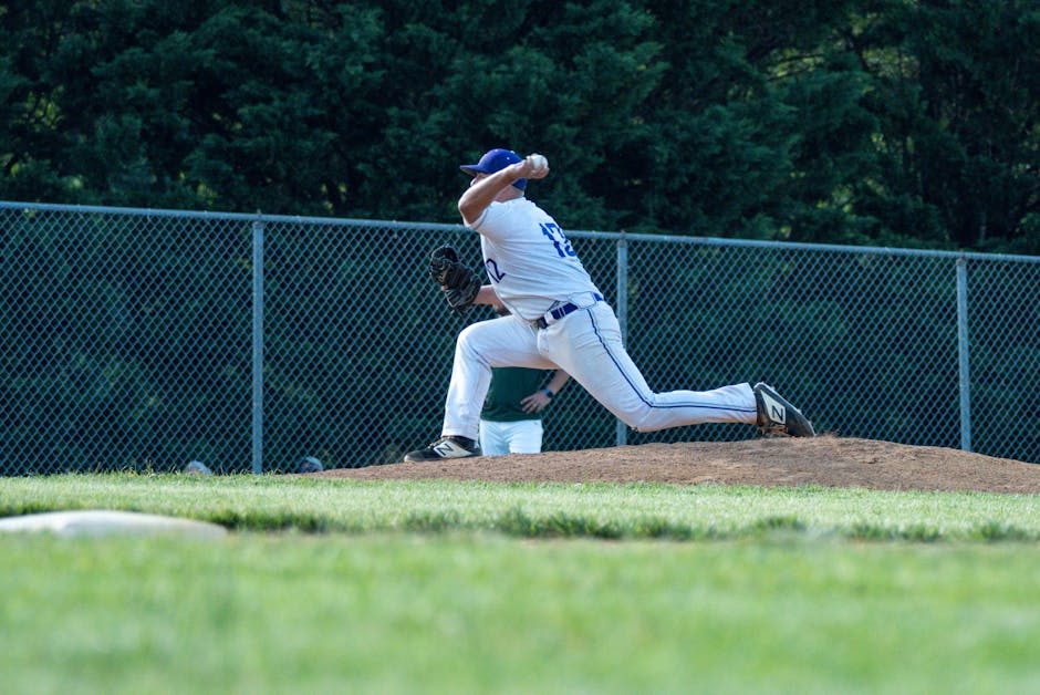 A baseball pitcher is captured in mid-throw on a sunny outdoor field.