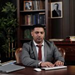 Corporate professional sitting at desk with American flag in office.