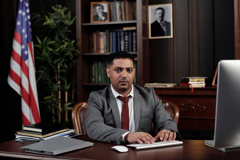 Corporate professional sitting at desk with American flag in office.