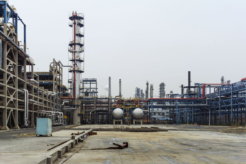 A detailed view of an industrial refinery featuring pipelines and large steel structures.