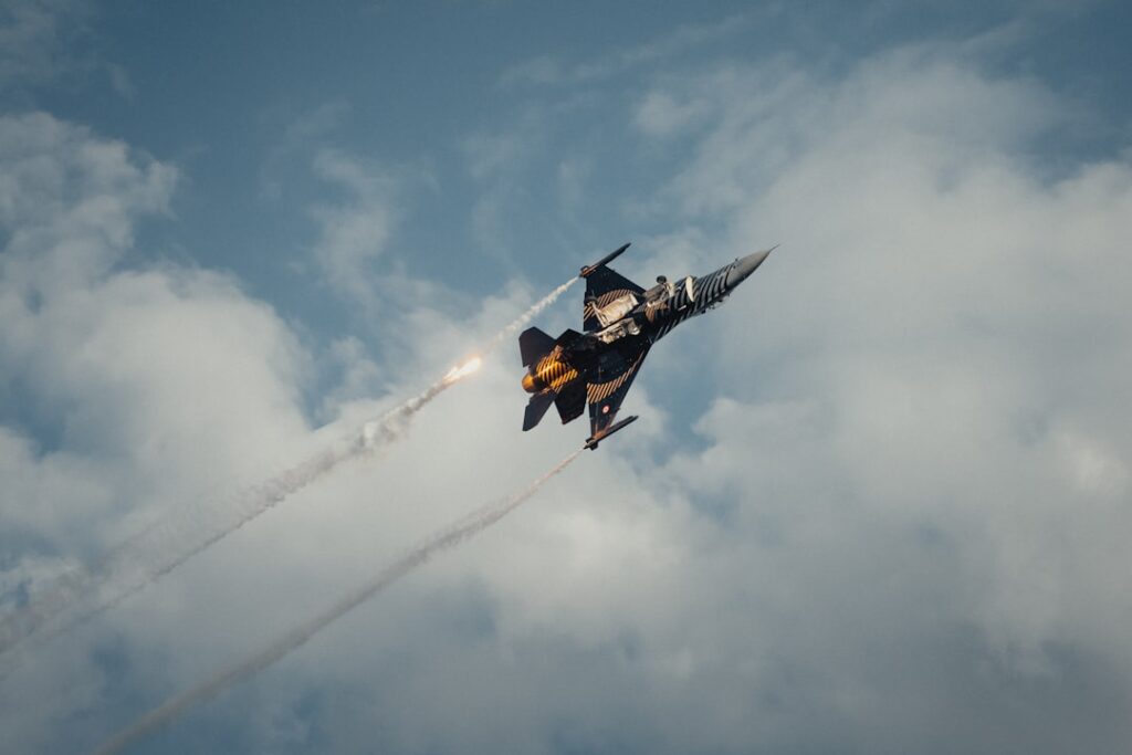 A fighter jet flying through a cloudy blue sky
