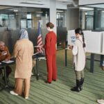 Diverse group of voters lining up at an indoor polling station on election day.