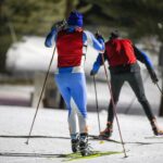 a couple of people riding skis down a snow covered slope