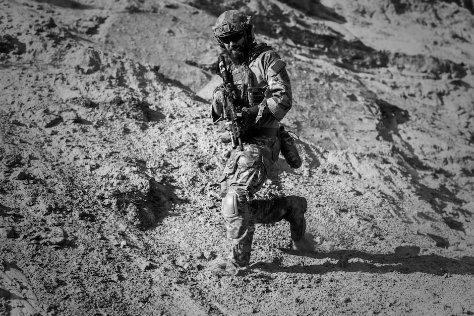 A soldier runs down a sandy hill in full combat gear under harsh desert sun.