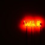 Bright neon WAR sign illuminating a dark space, conveying a strong message.