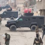 Armed forces in armored vehicles on the streets of Al Hasakah during a military operation.