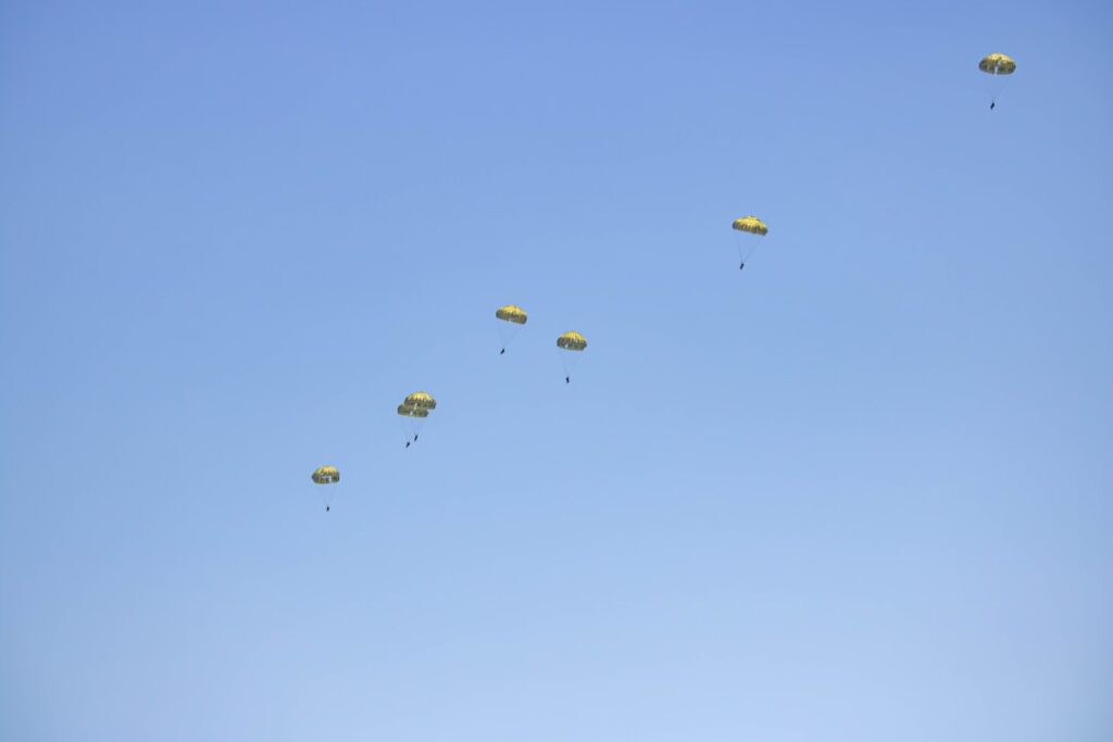 a group of yellow parachutes flying through a blue sky