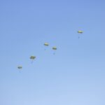 a group of yellow parachutes flying through a blue sky