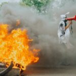 Protest scene with flames and megaphone speaker demanding attention amidst smoke.