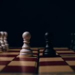 Close-up of chess pawns on a board in a strategic setup, capturing the essence of competition.