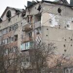 A damaged apartment building showing extensive artillery damage and decay.