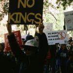 Protesters hold signs with messages against royalty.