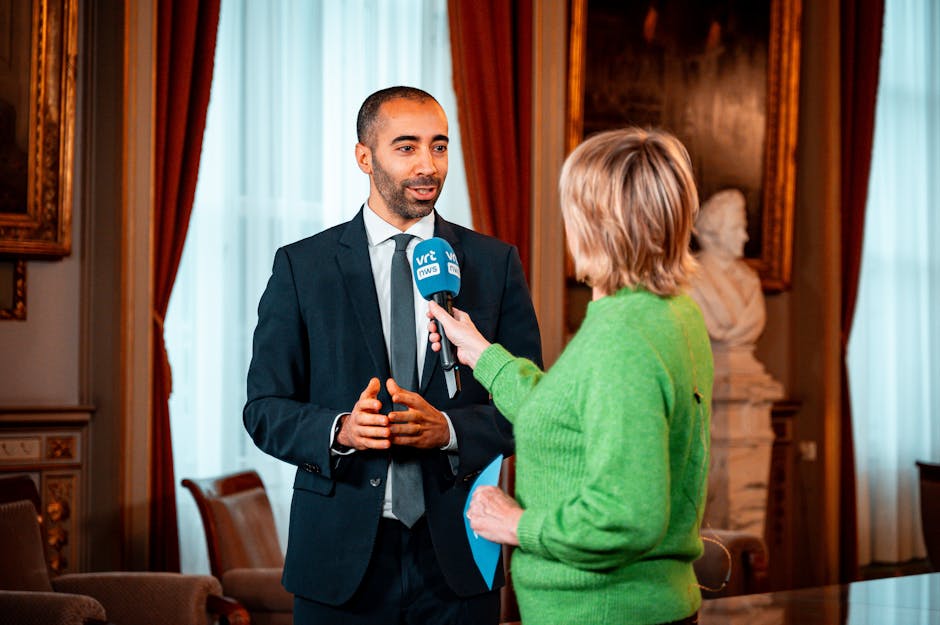 A journalist interviews a professional in a formal setting, highlighting media interaction.