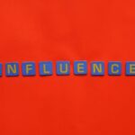 Bold blue letters spelling 'Influence' on a vibrant red background, conveying impact.
