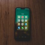 A smartphone showcasing various Google apps on a wooden table.