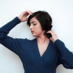 Serene portrait of a woman in a blue dress posing gracefully against white background.
