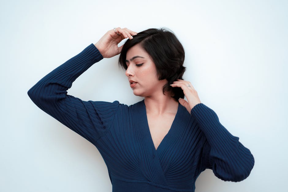 Serene portrait of a woman in a blue dress posing gracefully against white background.