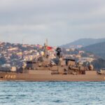 Turkish naval warship F240 cruising in the Bosphorus against an Istanbul cityscape.