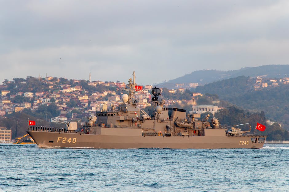 Turkish naval warship F240 cruising in the Bosphorus against an Istanbul cityscape.