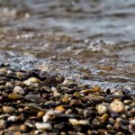 Close-up of pebbles with gentle ocean waves. Perfect for nature themes.