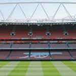 View of Arsenal's iconic Emirates Stadium with empty stands and lush football pitch.