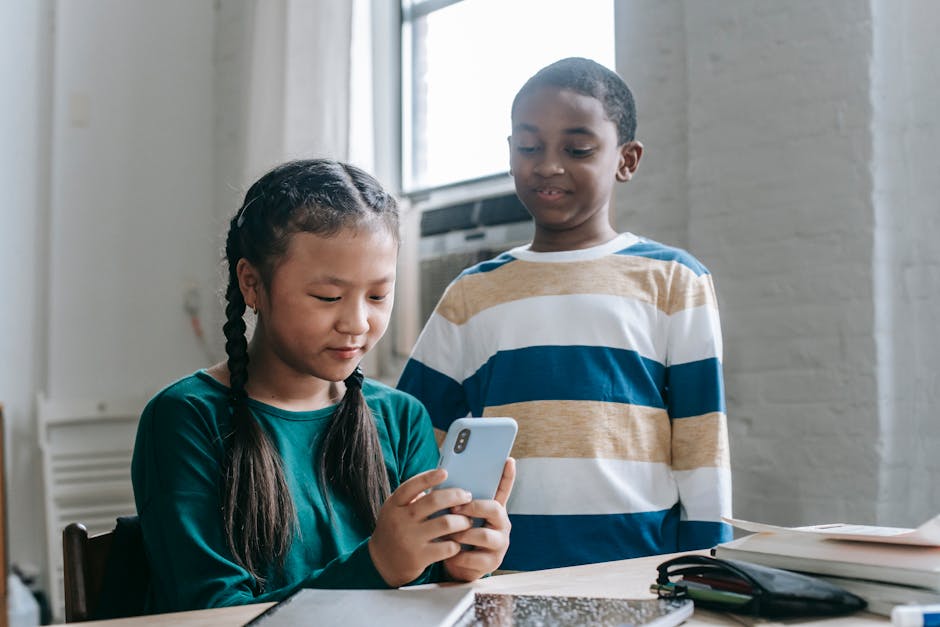 Two children engaged with a smartphone in an indoor educational setting.