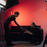 Behind-the-scenes view of a film crew in action, setting up a studio scene with lighting and equipment.