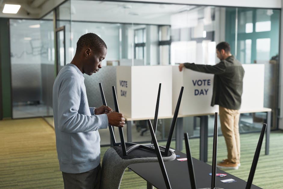 Men preparing voting booths indoors for election day, enhancing democracy.