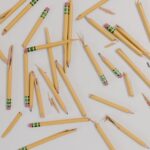 A flat lay of broken pencils scattered on a white background.