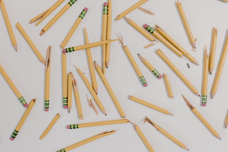 A flat lay of broken pencils scattered on a white background.