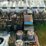 Drone view of industrial area with barrels for petroleum products and pipes connected with warehouses