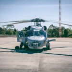 Military helicopter parked outdoors on a sunny day at a Brazilian airfield.