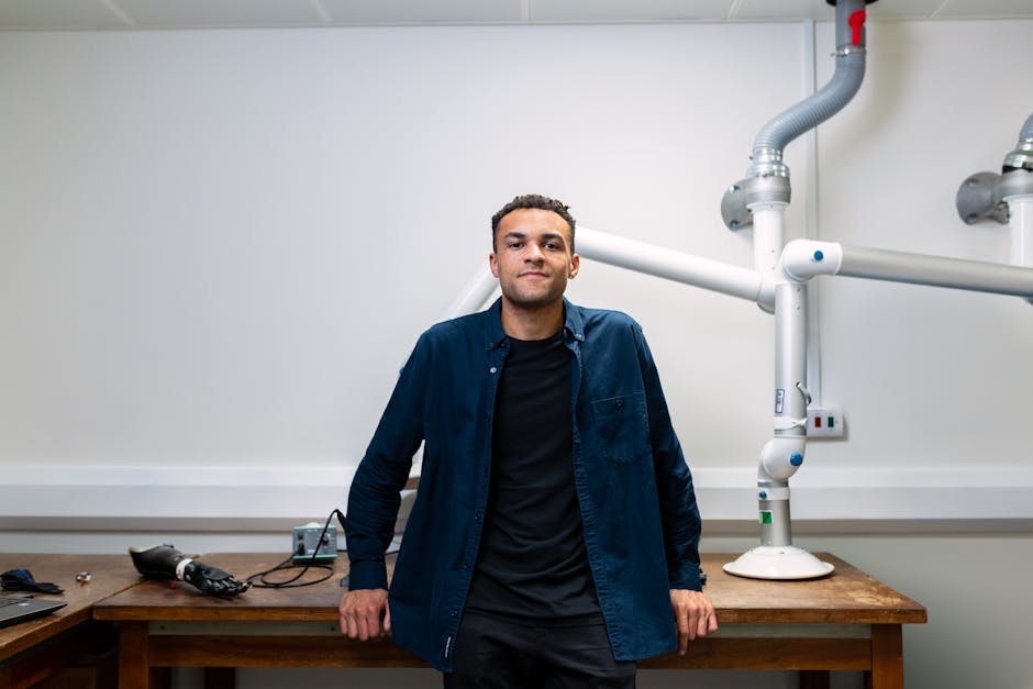 Confident young engineer standing in a laboratory with advanced robotic equipment.