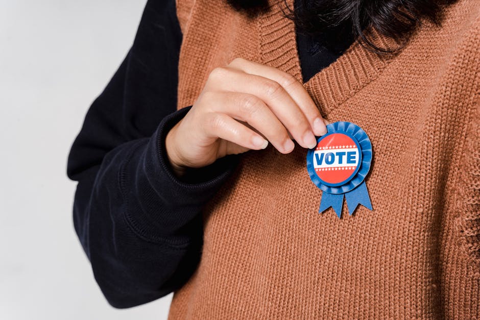 Person wearing a 'Vote' badge, symbolizing participation in democracy and elections.