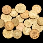 Assorted gold coins showcasing different currencies and designs isolated on a black background.