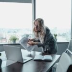 Professional businesswoman in modern office conducting virtual meeting with documents and laptop.