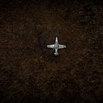 Top view of a vintage military aircraft abandoned in a field, showing decay.
