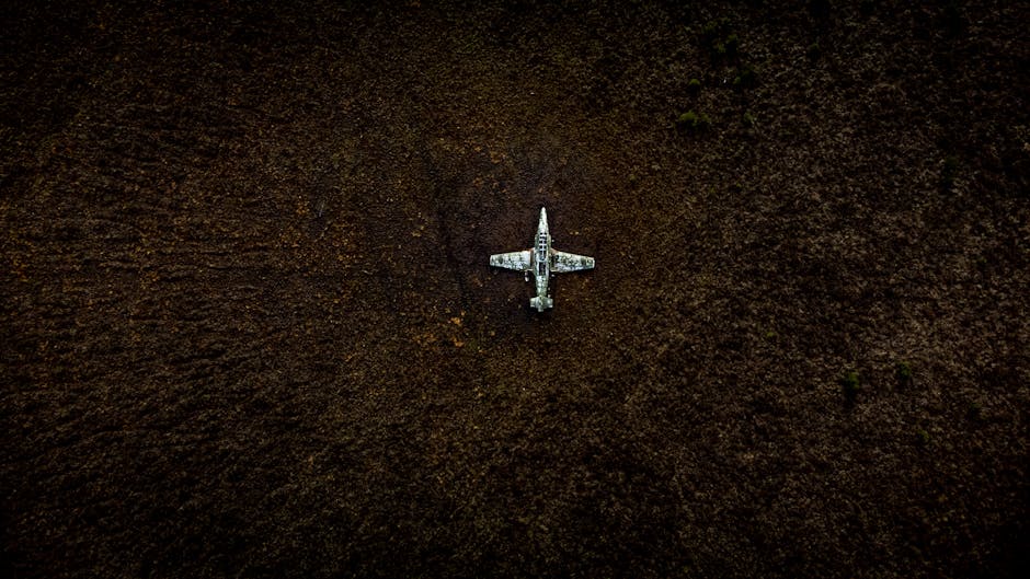 Top view of a vintage military aircraft abandoned in a field, showing decay.