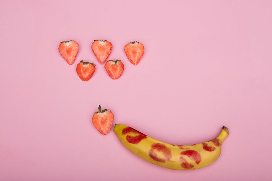 Creative conceptual display using bananas, strawberries on pink background, symbolizing sexuality and romance.