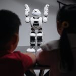 Two children observe a humanoid robot on a table, exploring technology and innovation.