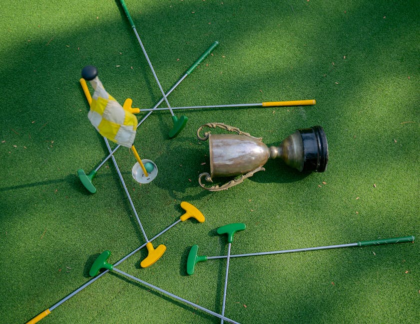 Mini golf setup with colorful putters, a cup, and a flag on green turf. Ideal for casual sports and recreation themes.