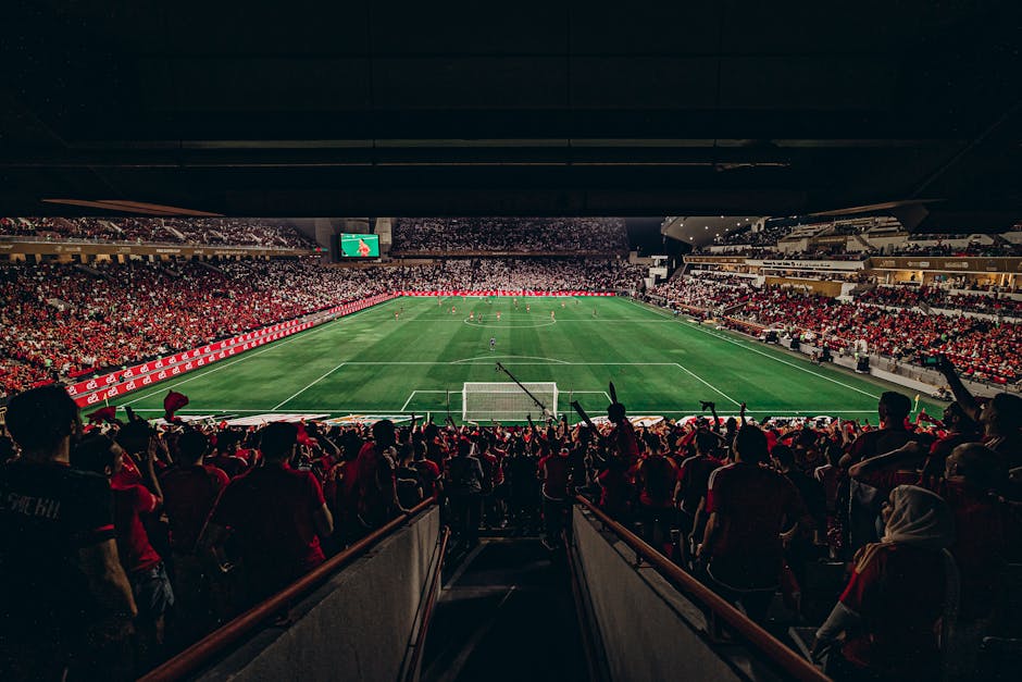 An exciting football match with passionate fans filling the stadium under bright lights, capturing sports energy.
