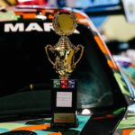 Golden trophy on a vibrant race car hood, symbolizing achievement in motorsports.