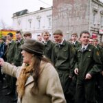 A group of soldiers in military uniforms marching in a street parade.