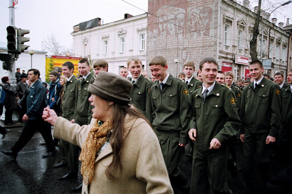 A group of soldiers in military uniforms marching in a street parade.
