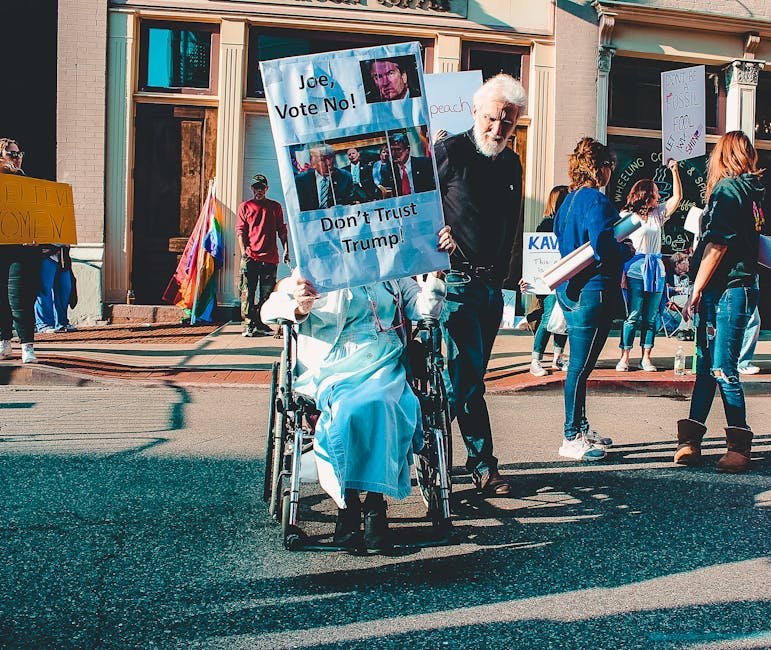 A diverse group of people protesting outdoors with signs and banners in a vibrant street scene.
