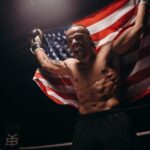 Triumphant boxer celebrates victory in the ring, holding an American flag.