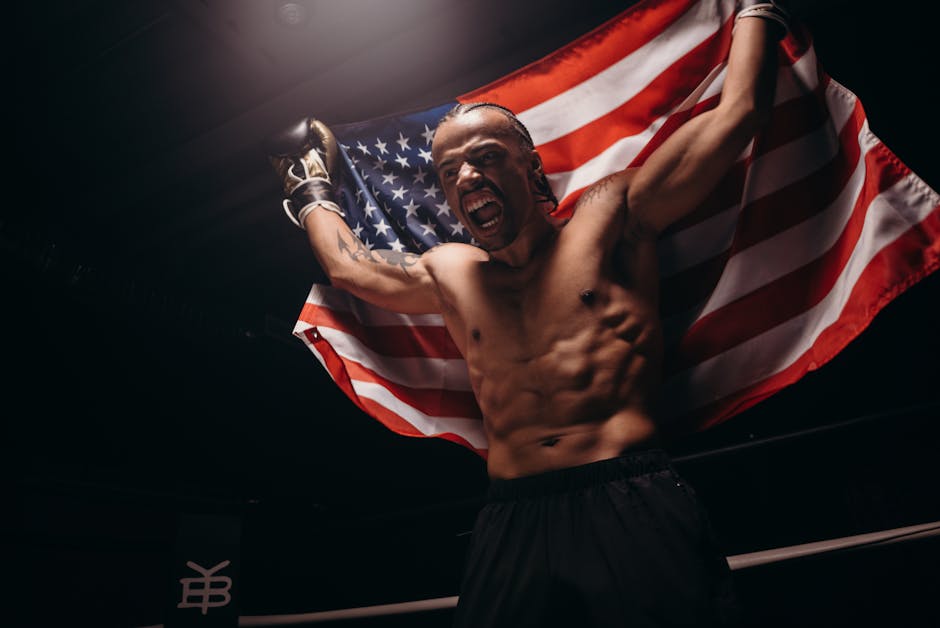 Triumphant boxer celebrates victory in the ring, holding an American flag.