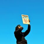 A protester raises a sign during a demonstration in Los Angeles under a clear blue sky.